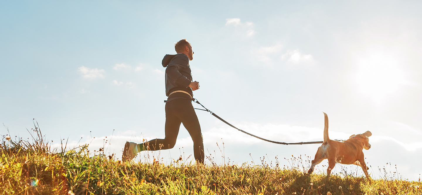 Jogger running in the countryside on a clear day with a dog on a lead