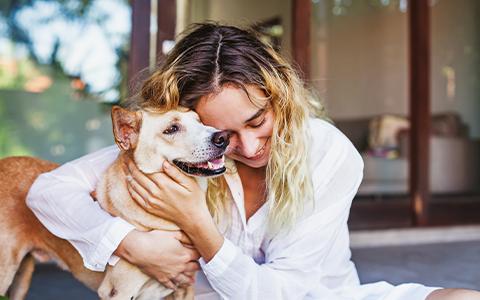 Woman sat on the floor lovingly hugging her dog